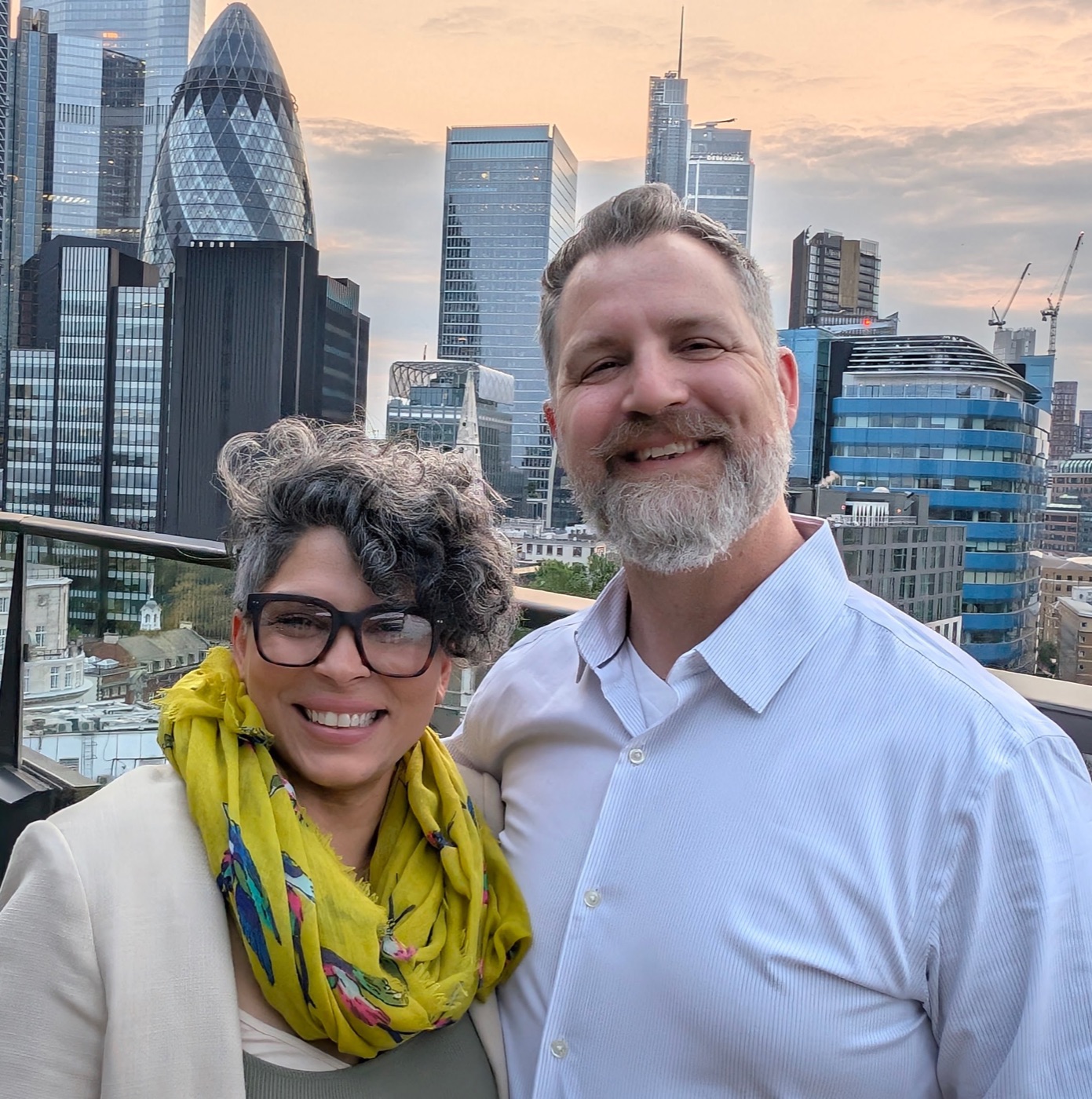 Shamain Webster and her partner Seth smiling on a rooftop terrace with the London skyline behind them