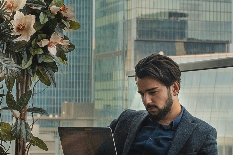 Executive in a blazer working on a laptop on a high-rise terrace